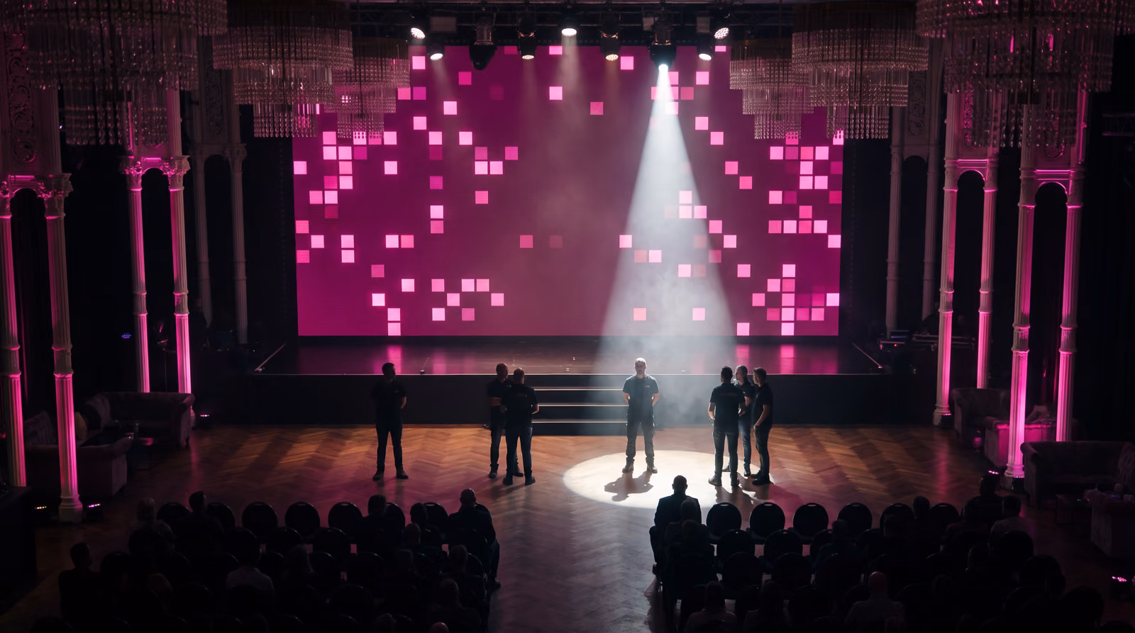 Silhouetten vor der Bühne der Flora, eine im Lichtkegel, dahinter die LED-Wand, der Saal im Dunkeln. KI-Visualisierung des geplanten Abends. Basis: echtes Foto der Flora Köln.