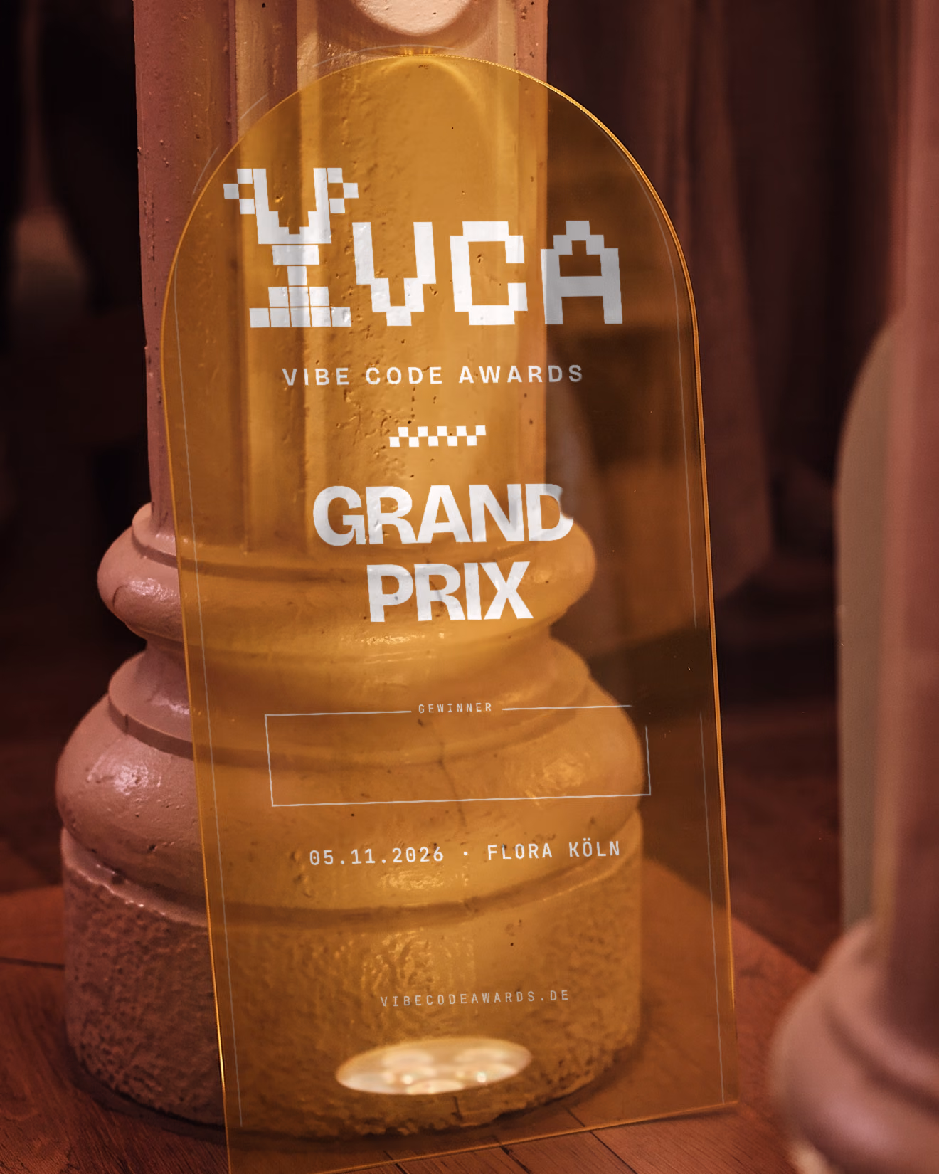 Der Grand-Prix-Pokal: ein goldenes Acrylschild mit dem VCA-Logo auf einem Holzsockel im Saal der Flora. KI-Visualisierung auf Basis des echten Pokals und eines echten Fotos der Flora Köln.